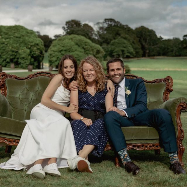 Happy couple sat on a sofa outside at a wedding planned by wedding planner Jenny Wren.