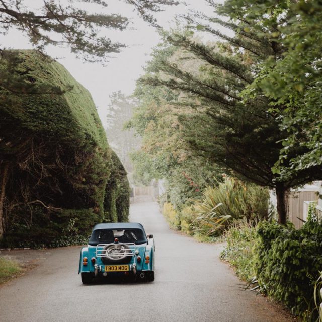 Blue wedding car driving down a country road. This wedding in Cornwall was planned by Jenny Wren - wedding planner.
