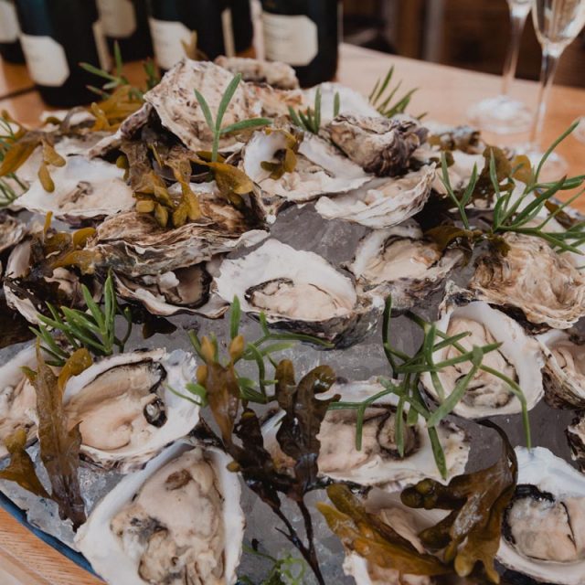 Close up of oysters decorated with chives and surrounded by champagne. This wedding in Cornwall was planned by Jenny Wren - wedding planner.