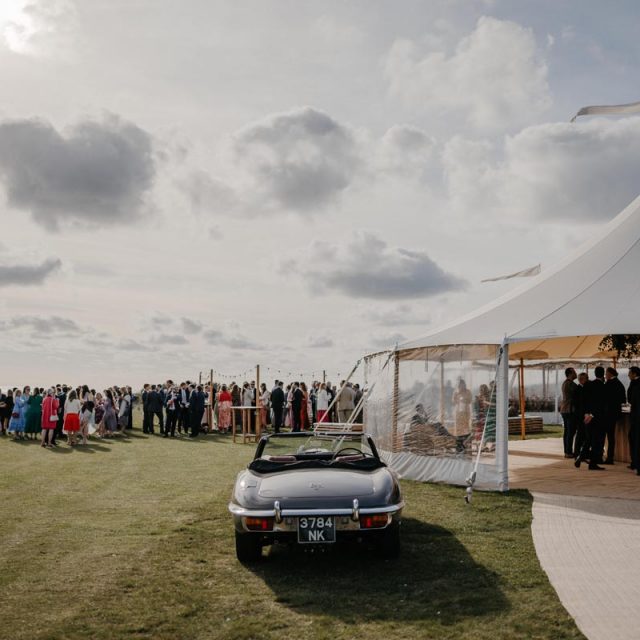 Wedding reception at Emma and Annie's wedding in Cornwall, with a car and gazebo in the foreground. This wedding was planned by Jenny Wren Wedding planner.